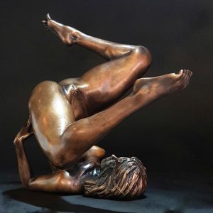 a small sculpture of a nude woamn on her back throwing her legs up.