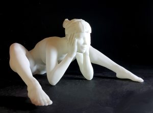 A white figurine of a nude woman siiting and leaning forward