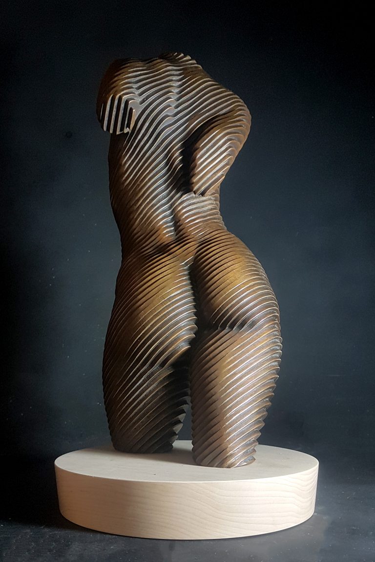 A bronze torso of a nude woman set on a wooden base