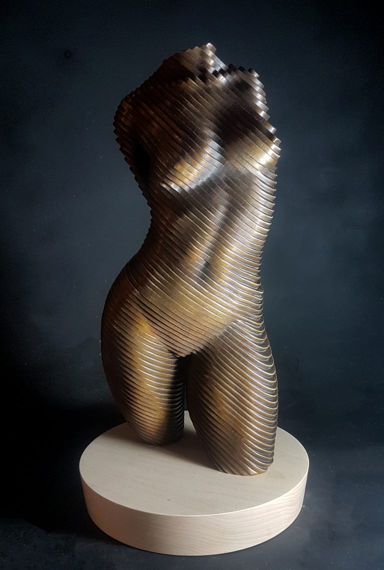 A bronze torso of a nude woman set on a wooden base