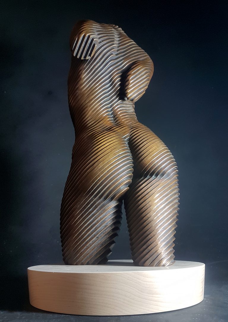 A bronze torso of a nude woman set on a wooden base