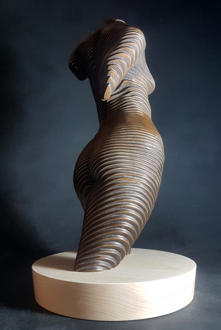 A bronze torso of a nude woman set on a wooden base