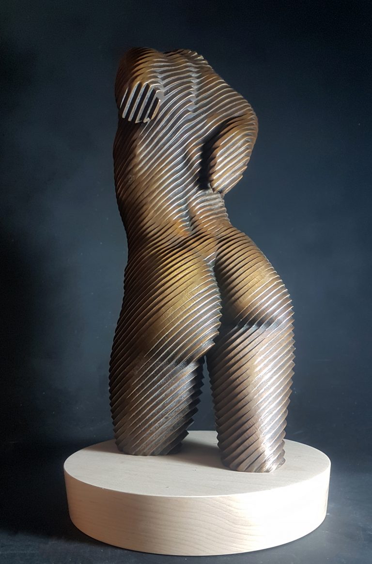 A bronze torso of a nude woman set on a wooden base