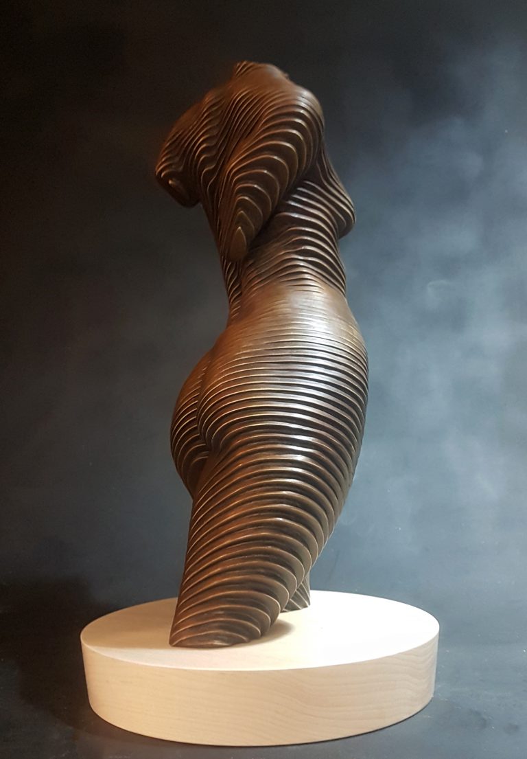 A bronze torso of a nude woman set on a wooden base